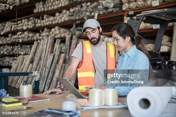 vrouw met laptop in magazijn met mannelijke werknemer kijken - factory owner stockfoto's en -beelden