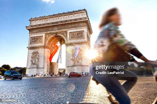 arc de triomphe in parijs met een grote franse vlag eronder - arc de triomphe parijs stockfoto's en -beelden