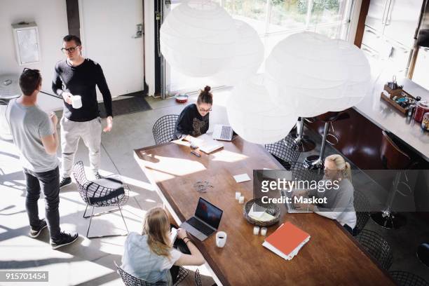high angle view of business people working in creative office on sunny day - co working stock-fotos und bilder