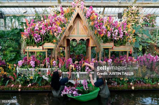 Employees pose with an orchid display during a photo call for the 'Orchid Festival' at the Royal Botanic Gardens in Kew, west London on February 8,...