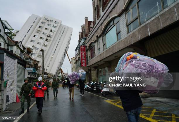 Volunteer carries a bag of blankets to a collapsed building in Hualien on February 8 after the city was hit by a 6.4-magnitude quake late on February...