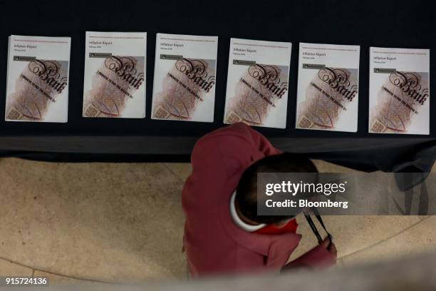 Member of the media walks past copies of the Bank of England quarterly inflation report ahead of a news conference at the Bank of England in the City...