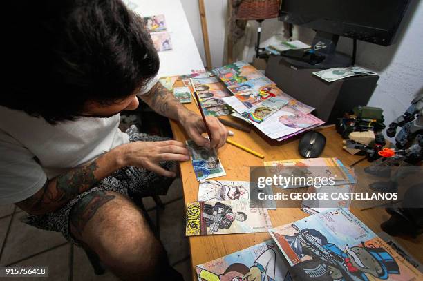 Venezuelan illustrator Jose Leon paints on devalued Bolivar bills, at his workshop in San Cristobal, Venezuela on February 2, 2018. Using devalued...