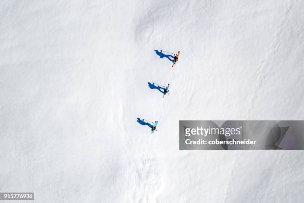 aerial view of three skiers and their shadows in the alps, sportgastein, salzburg, austria - kleine personengruppe stock-fotos und bilder