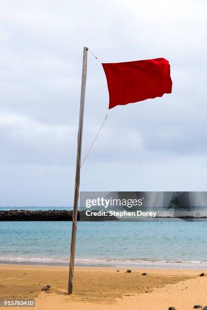 a red flag flying on the beach on the canary island of fuerteventura - caleta de fuste stock-fotos und bilder