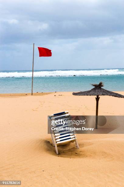 a red flag flying on the beach on the canary island of fuerteventura - caleta de fuste stock pictures, royalty-free photos & images