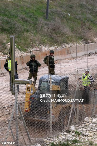Picture taken on February 8 from Lebanon's southern border town of Naqura, shows Israeli soldiers standing guard during the construction of a...