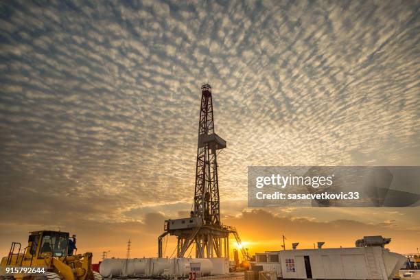 fracking broca de torre de perforación en puesta de sol - oil field fotografías e imágenes de stock