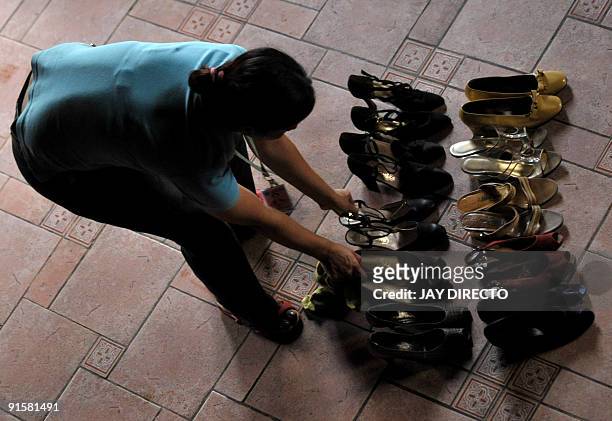 Museum worker cleans some of the shoes of Imelda Marcos at the Marikina Shoe Museum that were salvaged from deadly floods that swamped Manila on...