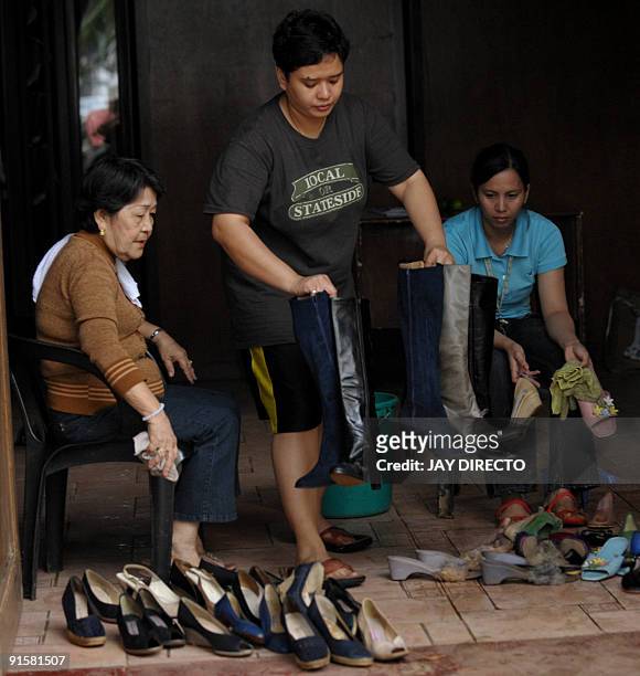 Museum official Sylvia de la Cruz , cleans some of the shoes of Imelda Marcos at the Marikina Shoe Museum that were salvaged from deadly floods that...
