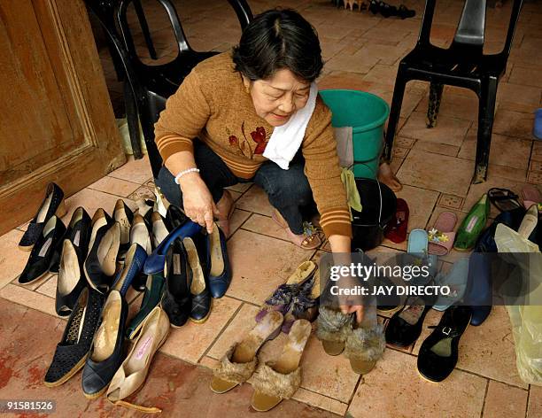 Museum official Sylvia de la Cruz 73, cleans some of the shoes of Imelda Marcos at the Marikina Shoe Museum that were salvaged from deadly floods...