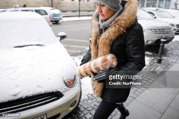 Woman is seen walking with a box of paczki, a type of donut traditionally consumed on Fat Thursday on February 8, 2018. Fat Thursday or Tlusty...