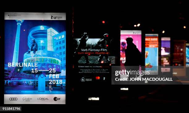 People walk past posters advertising the upcoming Berlinale film festival, including the festival's opening film "Isle of Dogs" by Wes Anderson, at...