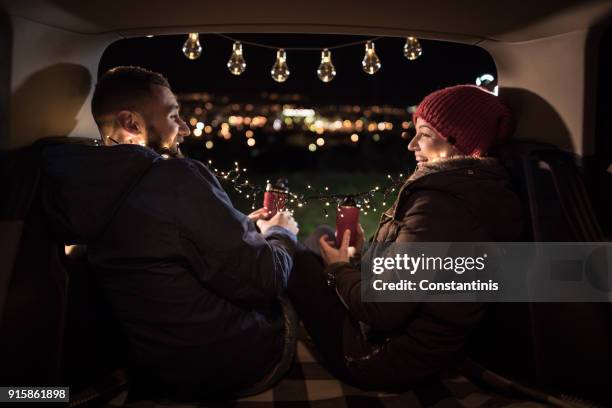 young couple in love sitting in car open trunk - driving romance stock pictures, royalty-free photos & images