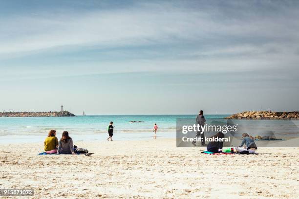 people vacationing and sunbathing on mediterranean beach during sunny winter day - herzliya marina bildbanksfoton och bilder