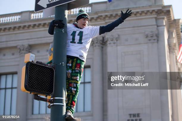 Fan climbs a light pole during the Super Bowl LII parade on February 8, 2018 in Philadelphia, Pennsylvania.