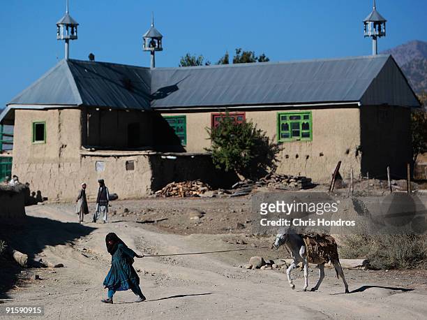 An Afghan girl leads a donkey near the town mosque October 8, 2009 in Dabay, Afghanistan. Dabau is a desperately poor agrarian ethnic Pashtun village...