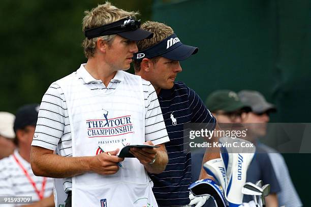 Luke Donald of England stands with his caddie and brother Christian Donald during the first round of THE TOUR Championship presented by Coca-Cola,...