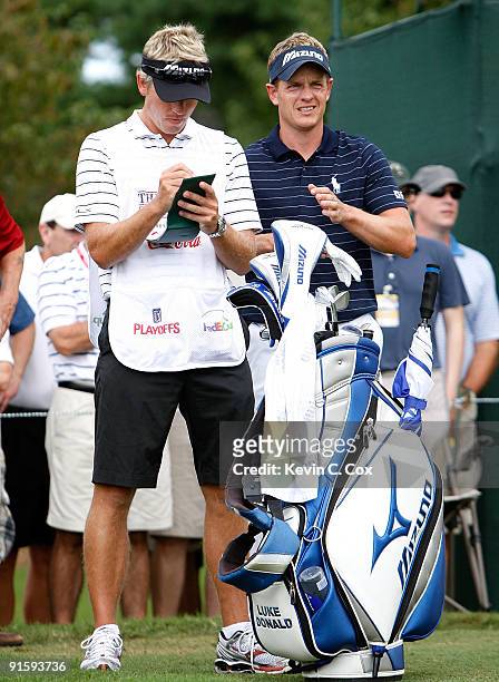Luke Donald of England stands with his caddie and brother Christian Donald during the first round of THE TOUR Championship presented by Coca-Cola,...