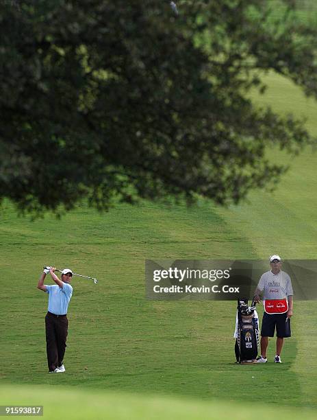 Mike Weir of Canada hits a shot while caddie Brennan Little looks on during the first round of THE TOUR Championship presented by Coca-Cola, the...