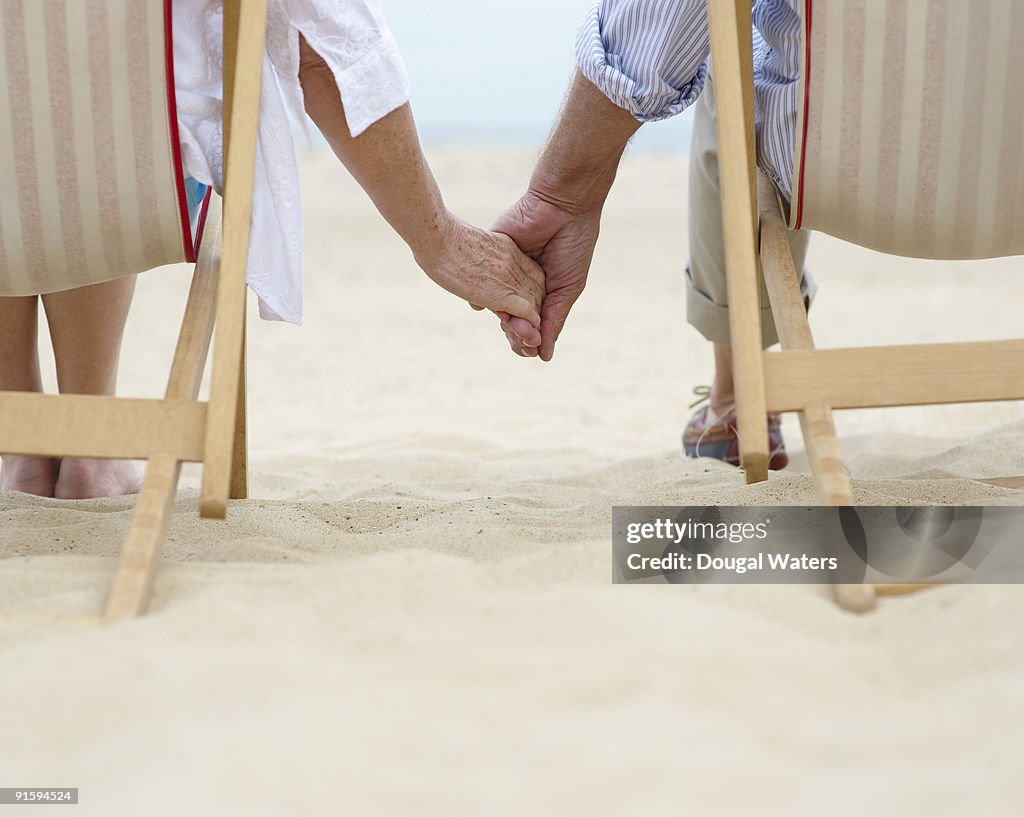 Elderly couple holding hands at beach.