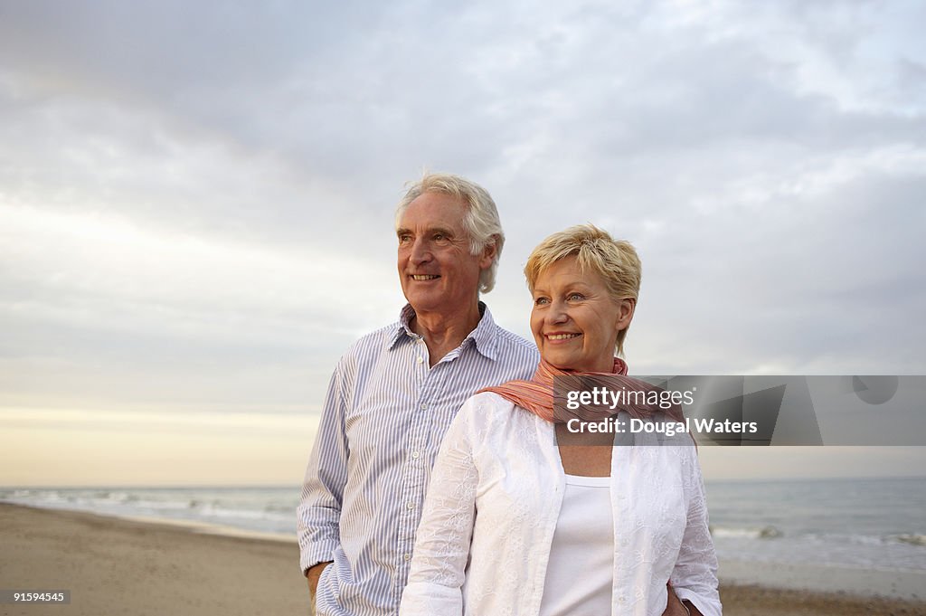 Elderly couple standing together at beach.