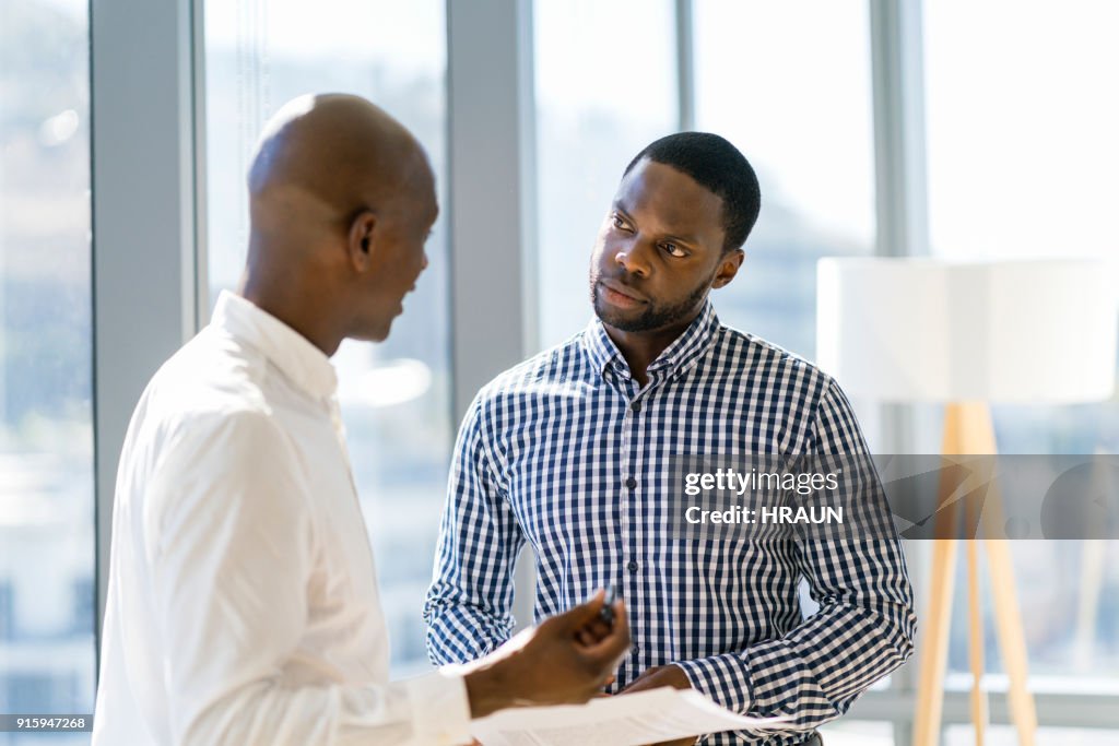 Male coworkers discussing over document at office