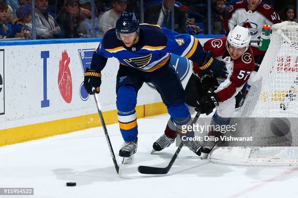 Carl Gunnarsson of the St. Louis Blues fights off Gabriel Bourque of the Colorado Avalanche while pursuing the puck at Scottrade Center on February...