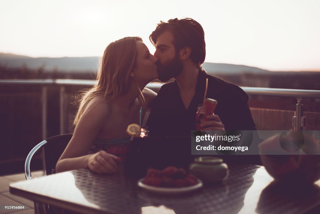 Beautiful couple enjoying sunset on the balcony and drinking fruit juice