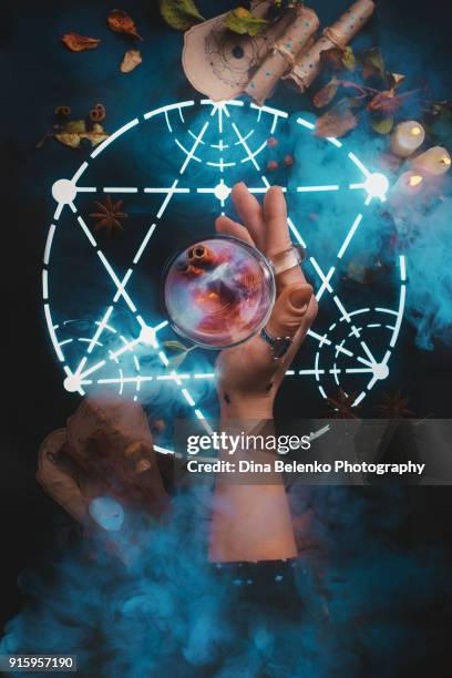 magical tea in young witch hand in the center of a glowing alchemical pentagram. dark still life with a hot beverage. conceptual food photography. - pentagramm stock-fotos und bilder