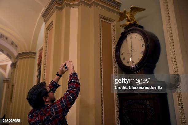 Senate staff members, journalists and others make photographs of the Ohio Clock as it shows midnight at the U.S. Capitol February 9, 2018 in...