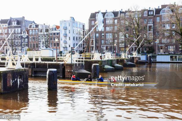 menschen ruderboot auf wasser-kanäle von amsterdam, niederlande - fluss amstel stock-fotos und bilder