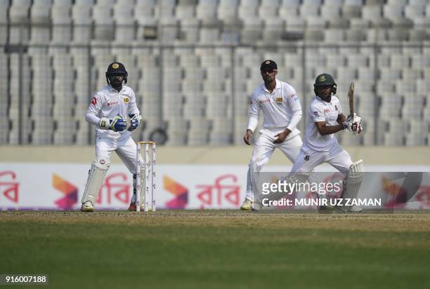 Bangladesh cricketer Mehedi Hasan plays a shot as Sri Lankan wicketkeeper Niroshan Dickwella looks on during the second day of the second cricket...
