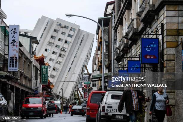 Pedestrians walk down a street that leads to the Yun Tsui building , which is leaning at a precarious angle, in the Taiwanese city of Hualien on...