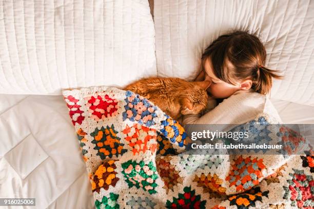 Girl having a nap on a bed with her cat