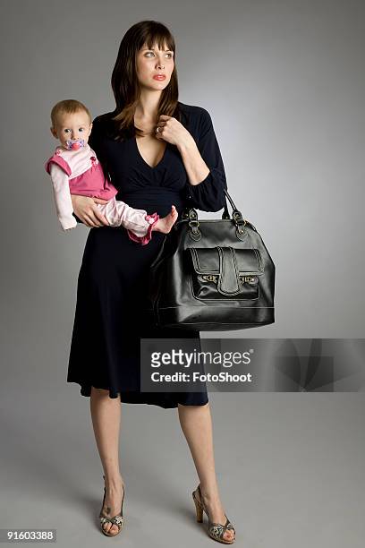 a working mom dressed in business attire holding her baby - studiofoto stock pictures, royalty-free photos & images