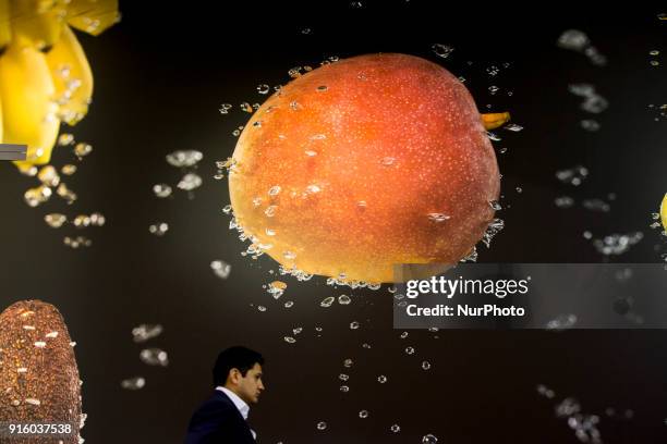 Man walks under the picture of fruits falling in water at the Fruit Logistica 2018 international vegetables and fruits trade fair in Berlin, Germany...