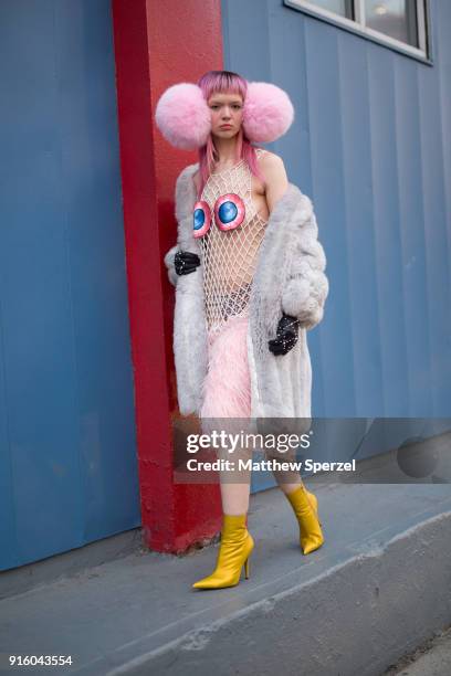 Liz Harlan is seen on the street attending Laurence & Chico during New York Fashion Week wearing oversized pink earmuffs, a grey fur coat, red/blue...