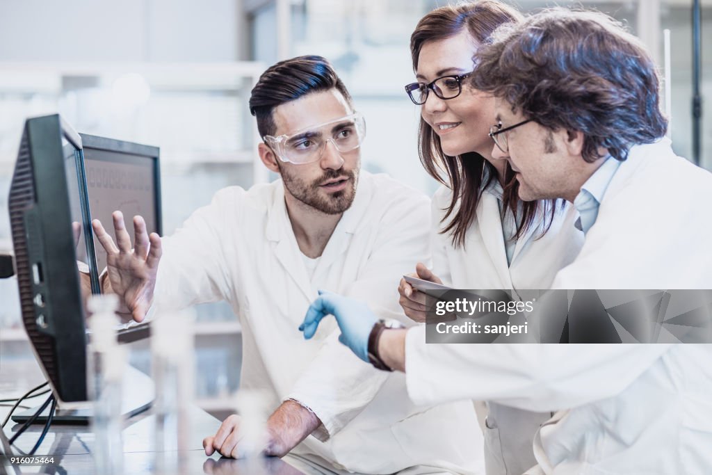 Forskare diskuterar i laboratoriet, använder dator