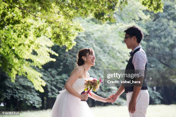 jeunes mariés vêtus de costumes de mariage détendus dans le parc - cérémonie du mariage photos et images de collection