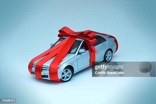 miniature toy car wrapped in red ribbon with bow - bow stockfoto's en -beelden