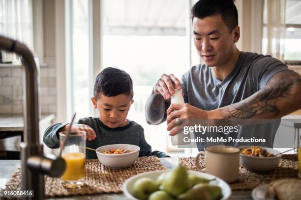 father and son having breakfast in kitchen - milk family stock pictures, royalty-free photos & images