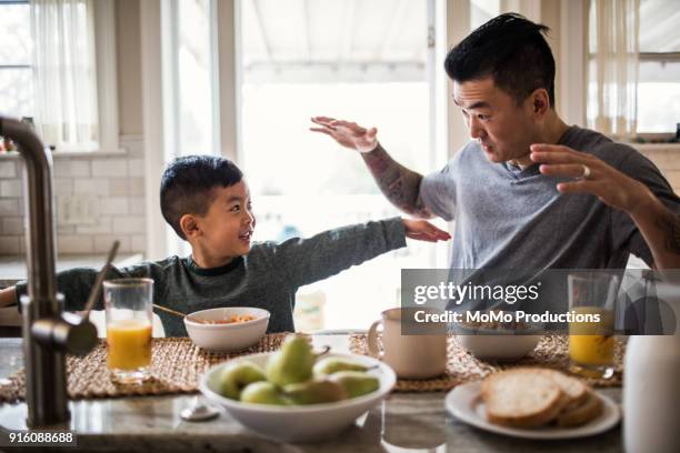 father and son having breakfast in kitchen - children eating breakfast stock-fotos und bilder