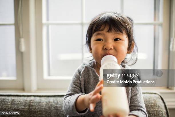 2 yr old girl with baby bottle - toddler milk stock-fotos und bilder