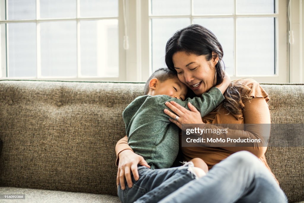 Mother hugging son on couch