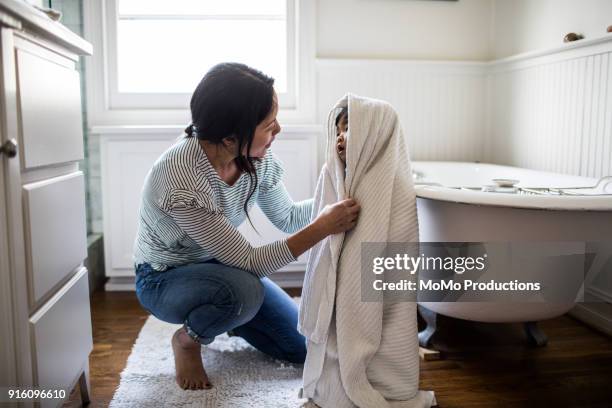 mother drying daughter off (2yrs) after bath - woman kneeling stockfoto's en -beelden