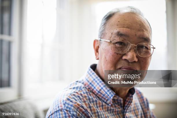 portrait of senior man at home - old asian man stockfoto's en -beelden