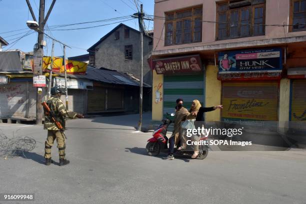 An Indian paramilitary trooper stops a scooterist during curfew in Srinagar. Authorities imposed restrictions in some parts of Srinagar on Friday...