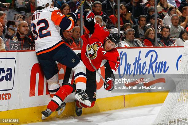 Mike Fisher of the Ottawa Senators checks Brendan Witt of the New York Islanders along the end boards during a game at Scotiabank Place on October 8,...