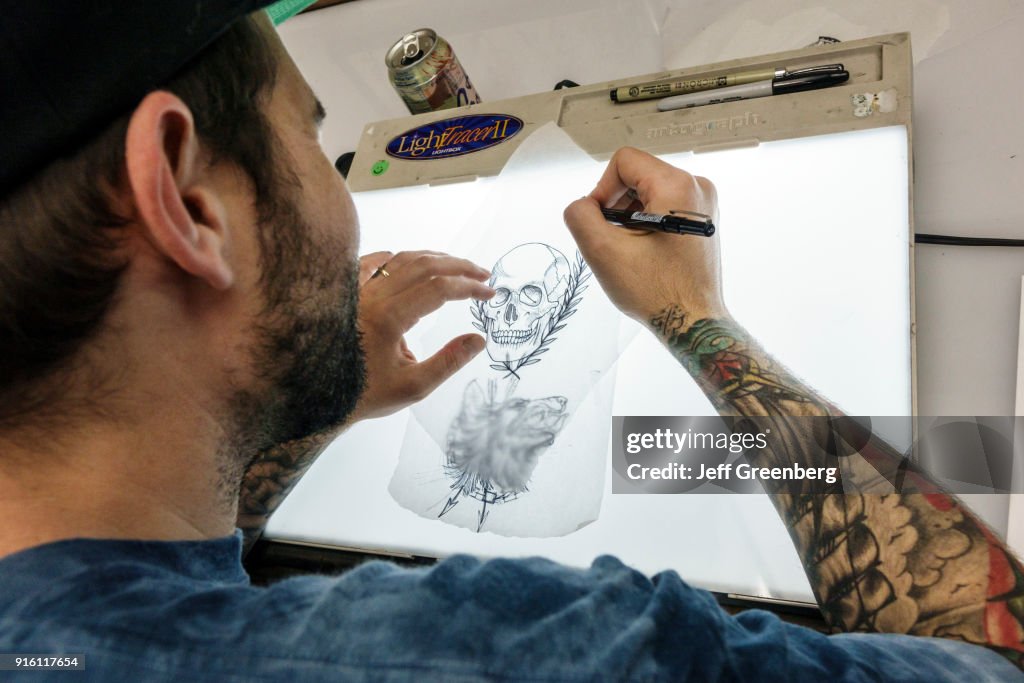 An artist drawing on a tracing light box in the Daredevil Tattoo Shop. News  Photo - Getty Images